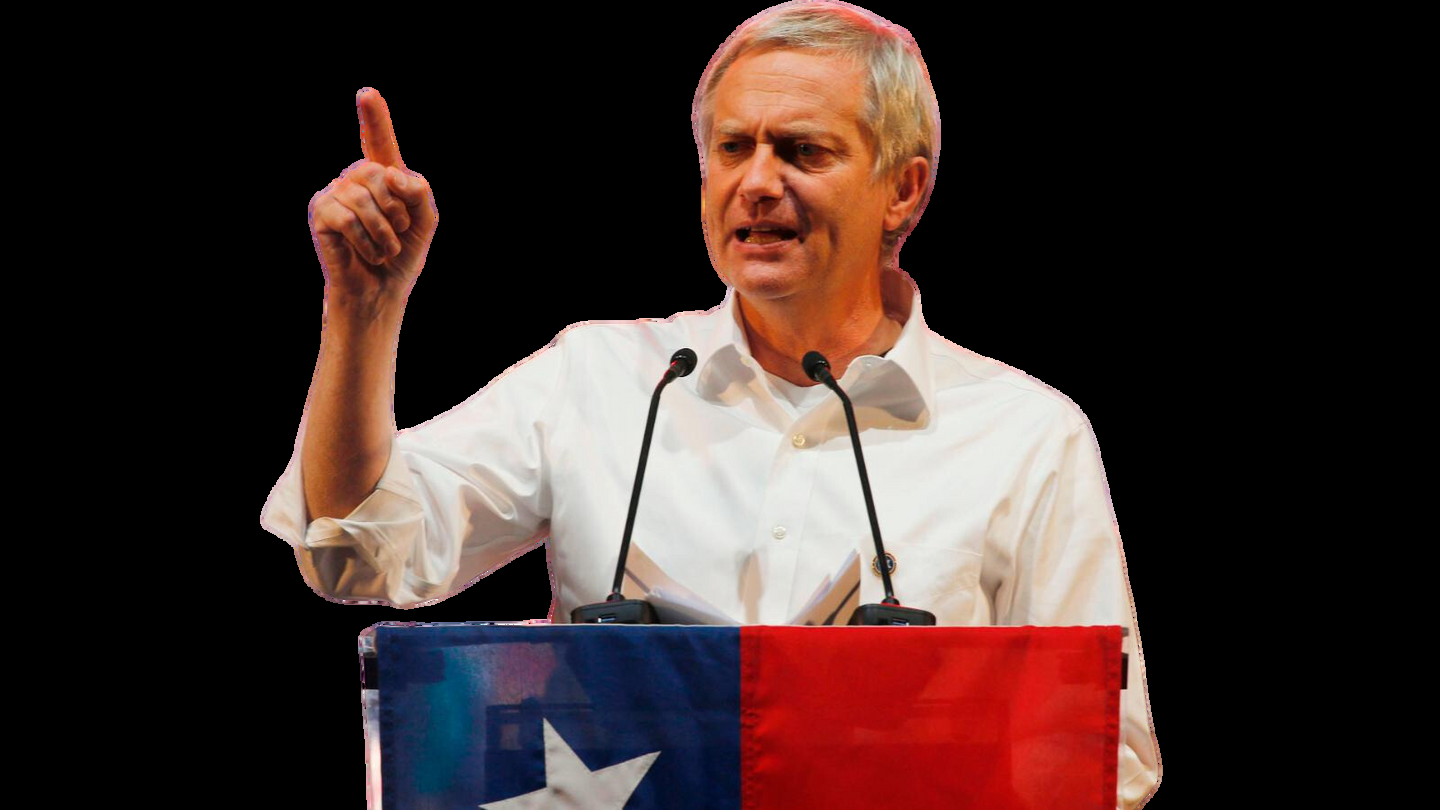 José Antonio Kast hablando desde un atril forrado con la bandera chilena, dedo índice en alto